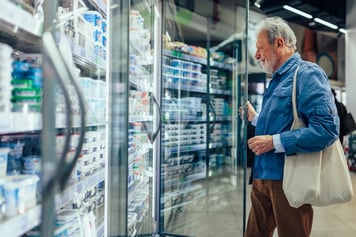 man looking in fridge at grocery store