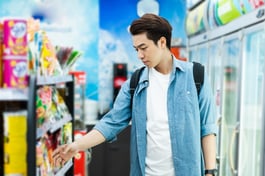 male shopper grabbing something off shelf in convenience store